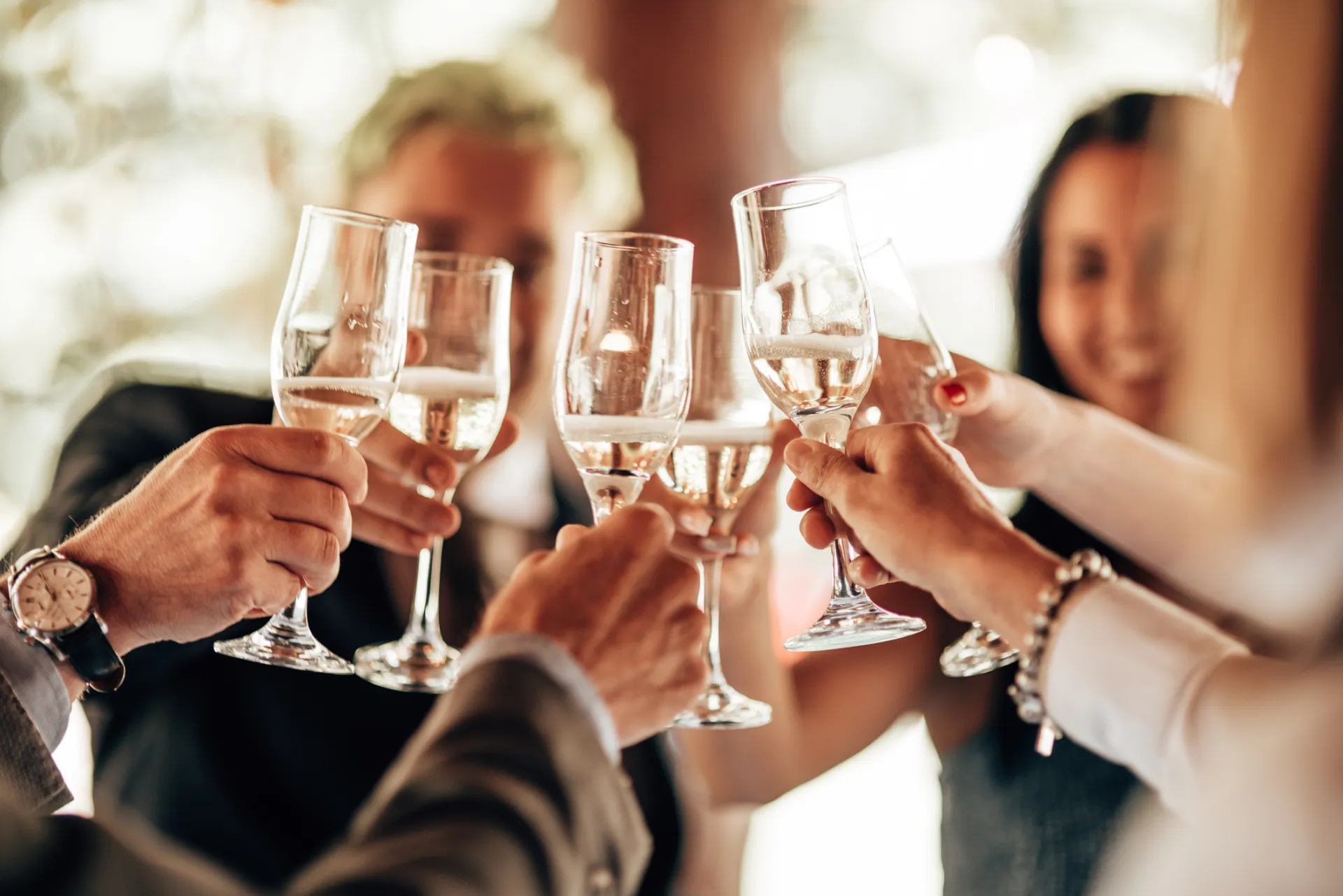 Eine Gruppe von Menschen stößt mit Sekt in Gläsern an.
